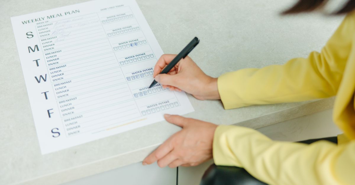 A family reviewing a shopping list together on a tablet at a kitchen table.